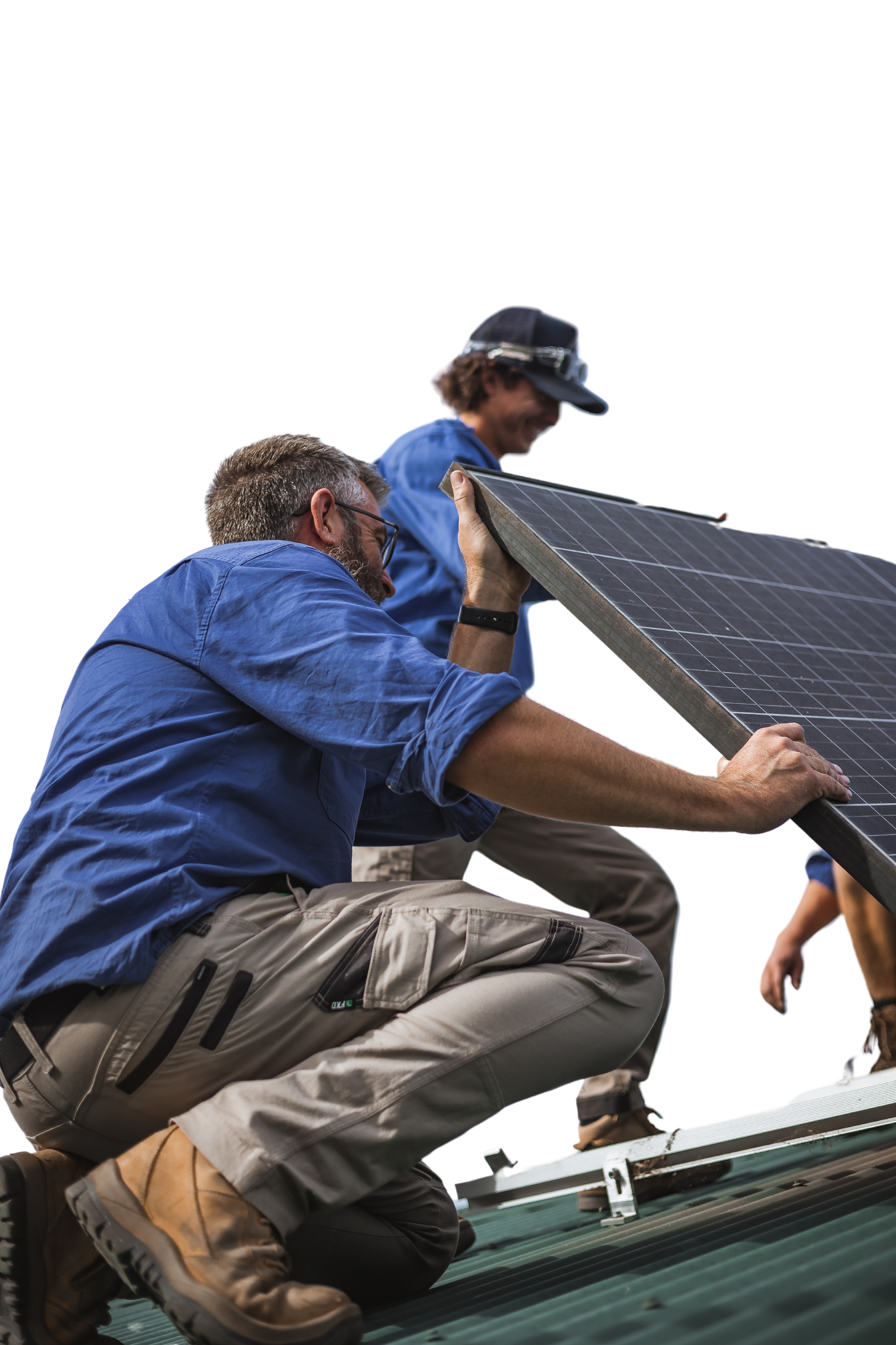 Two people in blue shirts install a solar panel on a rooftop. One is crouching while the other is standing behind, both focused on their task.